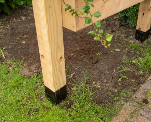 Wooden post with black tar treatment applied to its base where it meets the ground