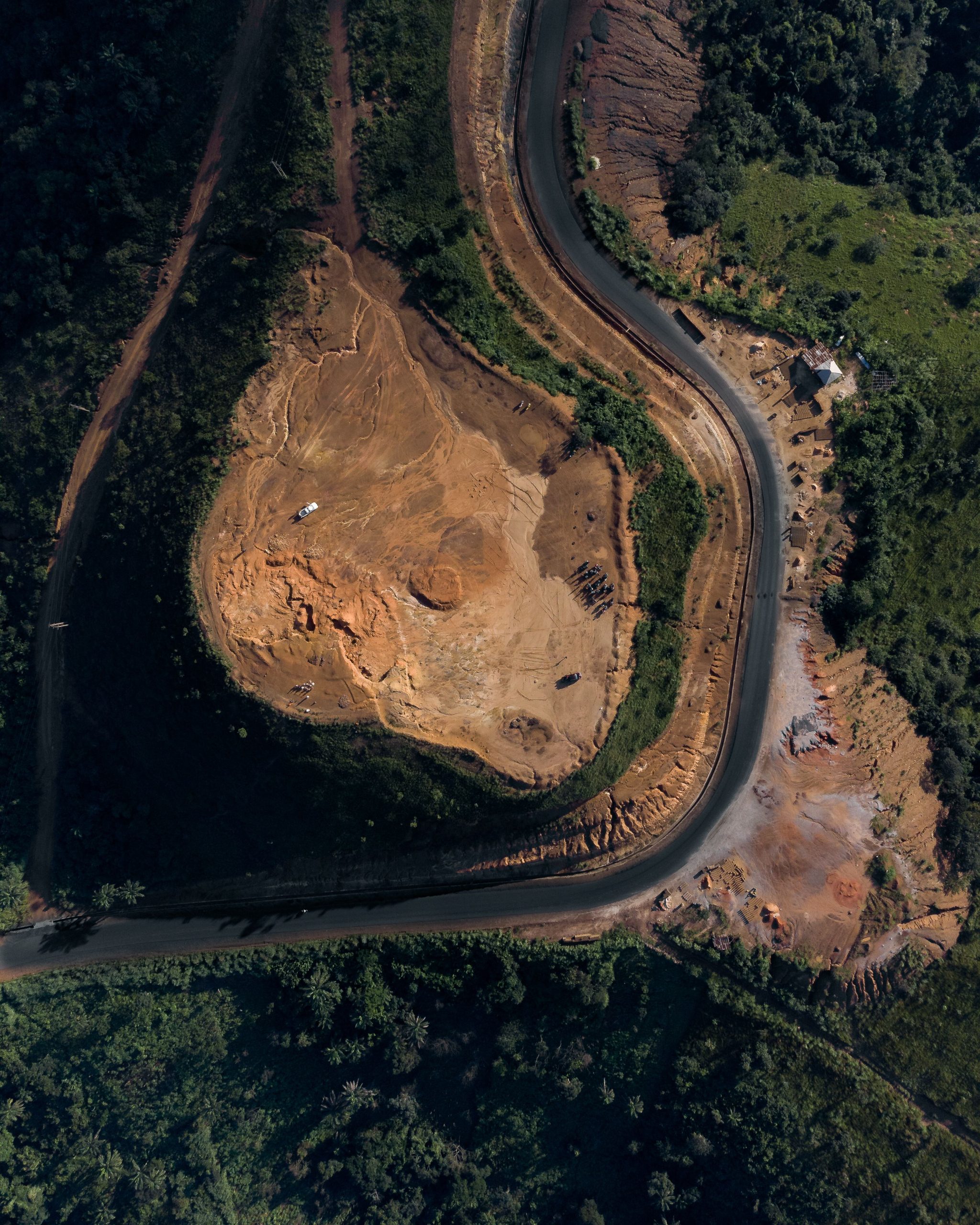 Aerial drone view of winding road beside a quarry — drone surveys are used for volumetric measurement and progress tracking in earthworks and quarrying operations